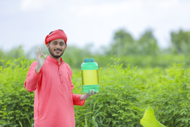 年轻的印度农民在绿地上展示肥料瓶图片下载