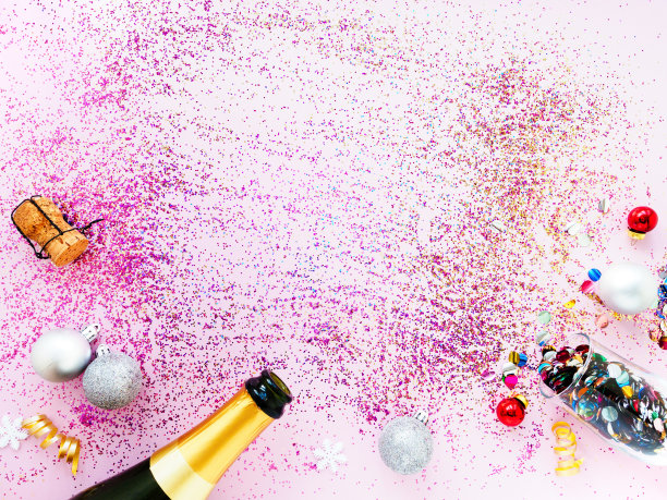 金色的香槟瓶，圣诞装饰品，亮片和粉红色背景上的五彩纸屑，平铺，复制空间，俯视图。圣诞节和新年的流行节日概念图片下载