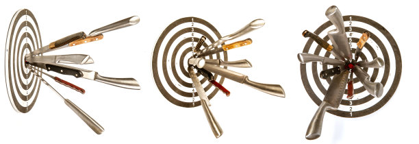 在白色背景上，一个木制目标的中央突出了许多锋利的钢制菜刀图片下载