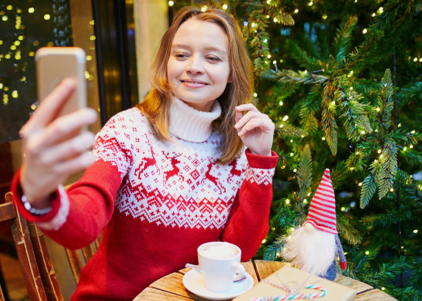 快乐的年轻女孩在节日毛衣与某人在圣诞节视频聊天图片下载
