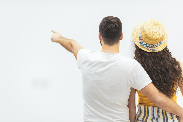年轻夫妇指着墙的后视图。图片下载