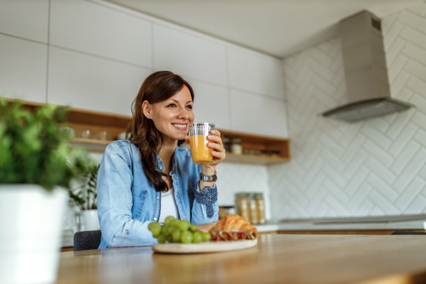 微笑的女人拿着和喝橙汁。图片下载