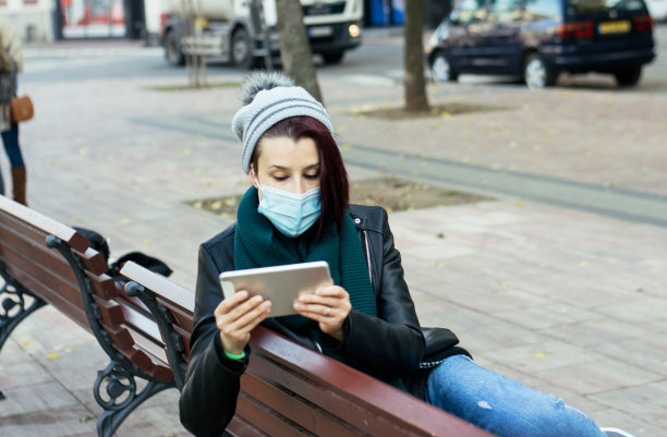 女人戴着面具使用数码平板电脑库存照片图片下载