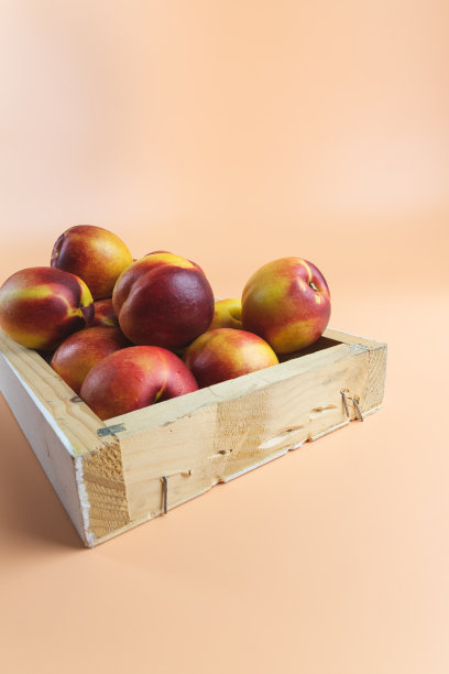 非常成熟的红色桃子，油桃里面有一个木盒出售。桃色的颜色的背景图片下载