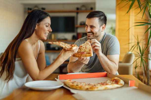 恩爱夫妻在家里吃披萨当早餐，肖像。图片下载