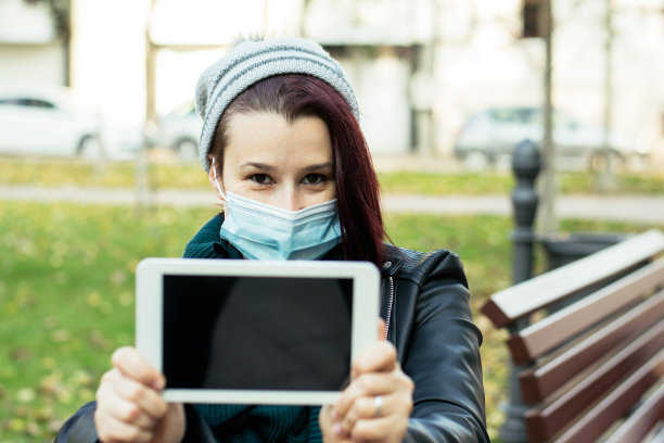 女人戴着面具使用数码平板电脑库存照片图片下载