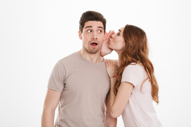 美丽的女人与美丽的赤褐色头发的照片在她的男朋友或熟人的耳朵闲谈男人，孤立在白色的背景图片下载