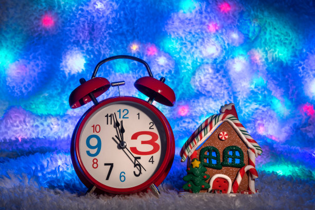 经典的红色闹钟站在由多色光点组成的背景上图片下载