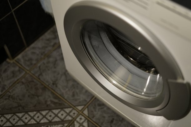 深色瓷砖地板上的白色洗衣机。图片下载