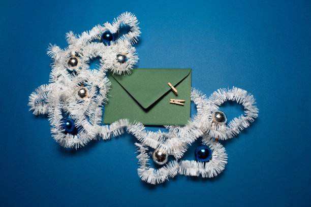 顶视图的绿色信封装饰与圣诞节的装饰品在蓝色的背景。图片下载