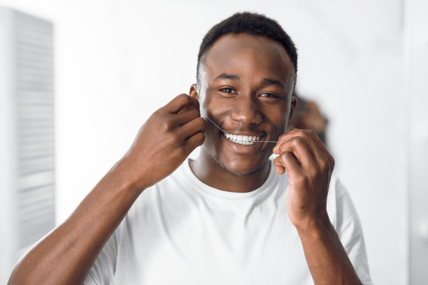 非洲人站在浴室里对着镜头微笑，用牙线剔牙图片下载