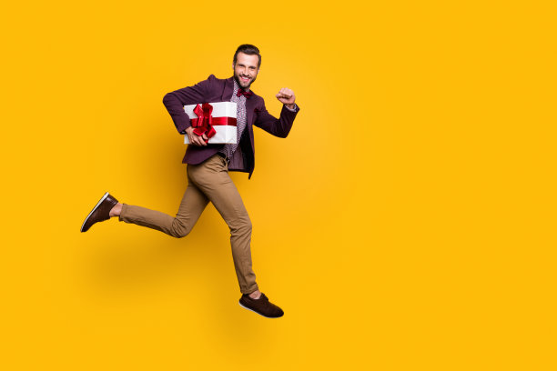 全尺寸的个人资料照片英俊的时尚的家伙跳高冲女朋友的生日聚会携带大礼盒穿格子衬衫运动裤鞋子孤立的黄色背景图片下载