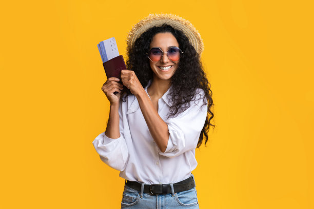 年轻的旅行者女子与护照和票在黄色背景图片下载