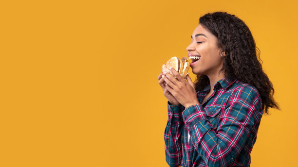 非裔美国女士在工作室吃汉堡的肖像图片下载