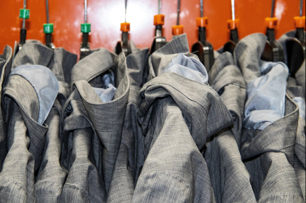 浅色的灰色雨衣放在架子上，背景是橙色图片下载