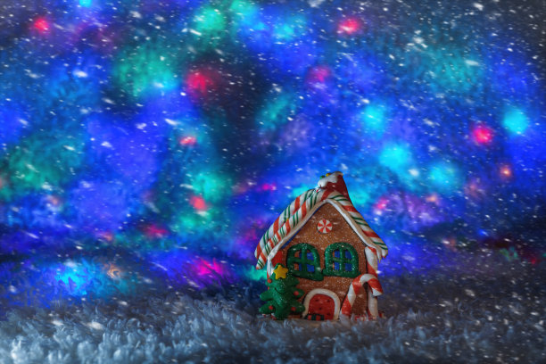 一个姜饼屋，窗户被照亮，背景是多色的灯光图片下载