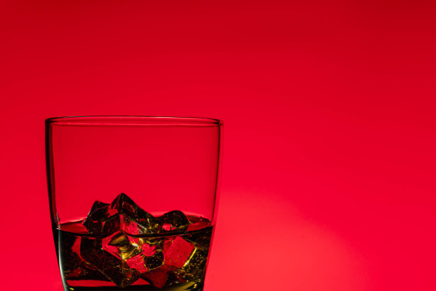 一杯带有红色背景冰块的威士忌图片下载