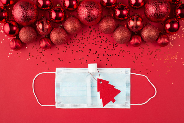 圣诞节和检疫概念。顶部以上的俯瞰近距离照片美丽装饰红色的小玩意，纸屑面具和洗手液与圣诞树形状的标签孤立在红色的背景图片下载