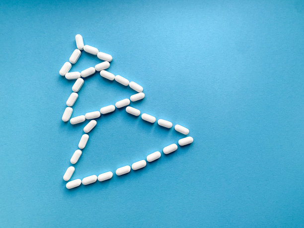 圣诞树是用蓝色背景上的白色药丸做成的。从上面的照片。圣诞树上的维生素可以增强免疫系统，是一份新年礼物。图片下载