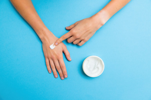 一位女士用食指在手部涂抹白色霜图片下载