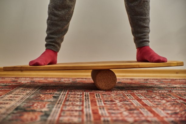 站在木制平衡板上的人。在平衡板上平衡的人。图片下载