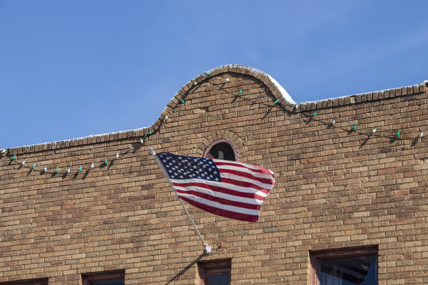 美国国旗从复古的西南风格的砖建筑立面挂着派对灯图片下载