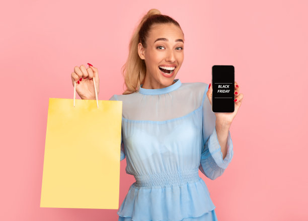 “黑色星期五”。兴奋的女人拿着购物袋和手机图片下载