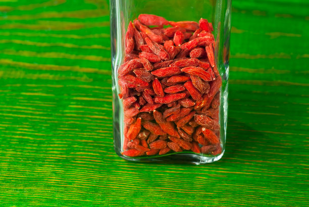 枸杞在一个罐子靠近。破旧的木板上有很多红浆果。图片下载