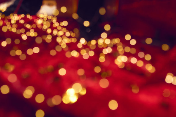 红色背景上模糊的金色节日灯光。图片下载