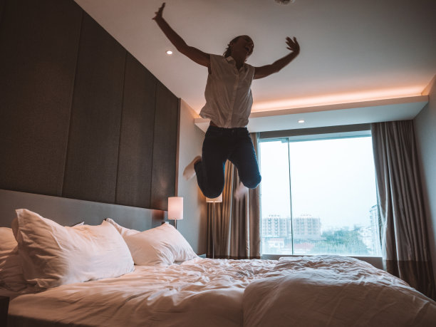 一个女人在房间的床上跳图片下载