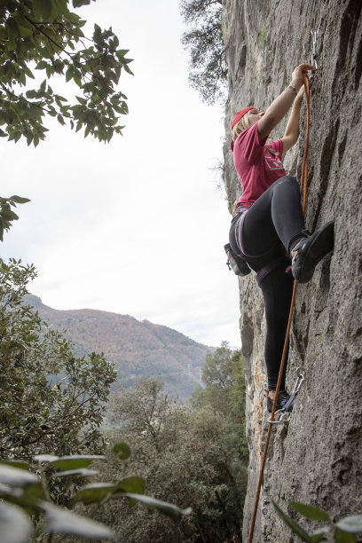 年轻女子在早晨爬上岩壁图片下载