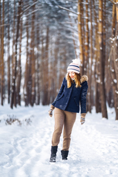 年轻的女士在冬天的衣服摆姿势与快乐在公园外面。图片下载