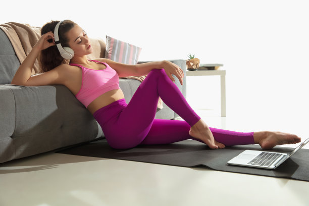 美丽的年轻女子在室内锻炼，在灰色垫子上做瑜伽练习图片下载