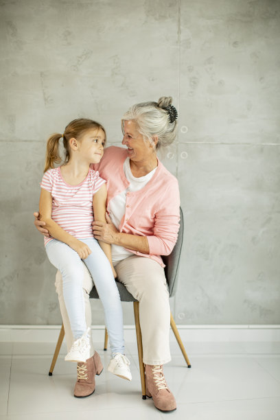 小女孩和她的祖母坐在靠墙的椅子上图片下载