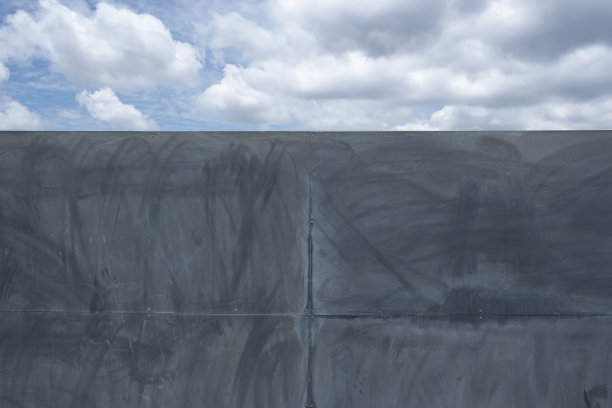 抽象的背景，风化的金属面板黑色，分裂组成与多云的蓝天图片下载