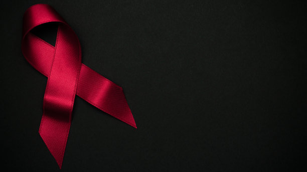 患有乳腺癌的女性。黑色背景上的红色丝带符号。认识艾滋病和癌症。保健和医疗概念。图片下载