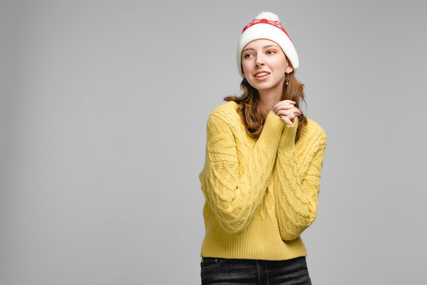 女人戴着红色的圣诞老人帽。新年女性肖像在工作室与孤立的背景。图片下载