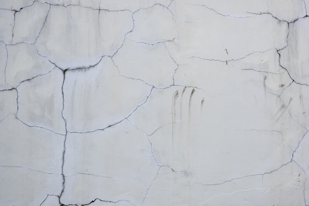 白色的墙壁有裂缝和粗糙的纹理。抽象的背景。股票的照片。图片下载