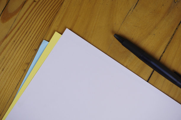 木桌上放着白纸和笔。复古复制空间背景概念图片下载