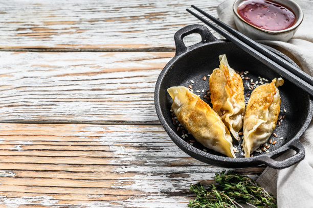 在平底锅里煎饺子，中国菜烹饪。白色背景。前视图。本空间图片下载