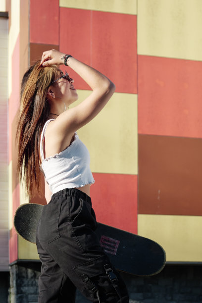 年轻的女孩抚摸着她的长发，拿着她的滑板图片下载