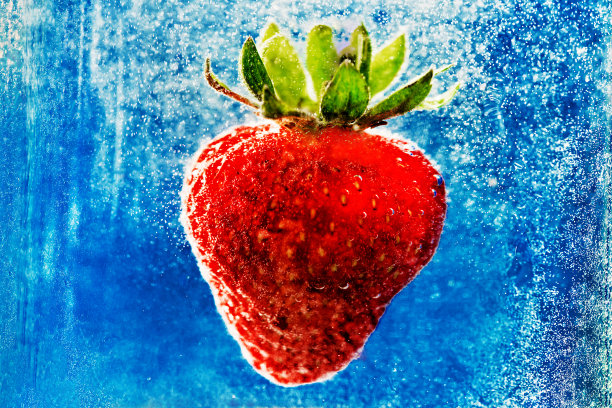 草莓带着泡泡掉进蓝色的水里。图片下载