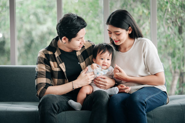 快乐的爸爸和妈妈抱着小宝宝一起玩。幸福家庭家庭生活理念。图片下载