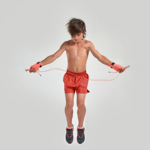 小体育男孩拳击手与拳击绷带在他的手，使用跳绳，跳跃孤立在白色的背景图片下载