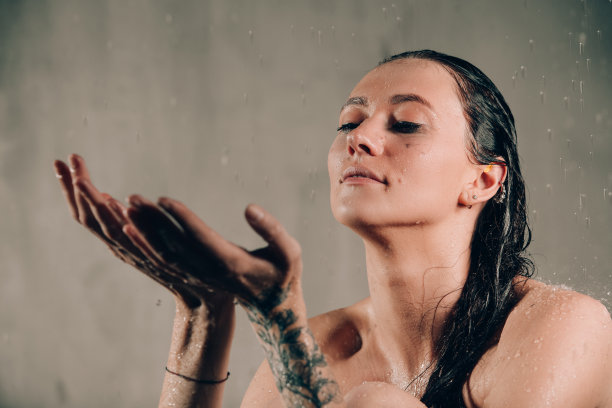 年轻漂亮的黑发女人在水和花中沐浴。模特在一个不寻常的照片拍摄在一个黑色的浴缸图片下载