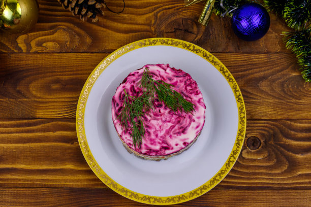 传统的俄罗斯沙拉“皮草下的鲱鱼”(舒巴)和木制桌子上的圣诞装饰品。俯视图图片下载