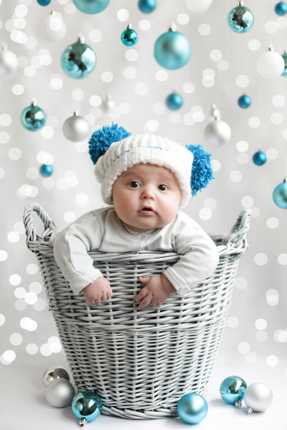 可爱的婴儿在帽子周围的蓝色圣诞球在白色的圣诞背景图片下载