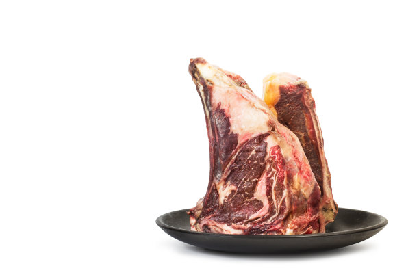 两块小牛排放在一个黑色的盘子里，孤立在白色的背景上图片下载