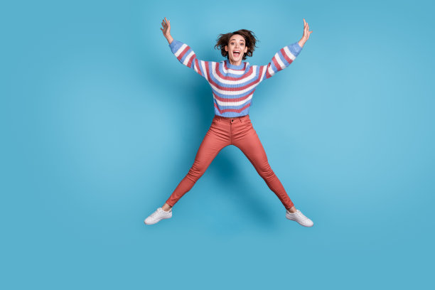全身大小的照片，粗心的女孩跳起来像一颗星孤立在明亮的蓝色背景图片下载