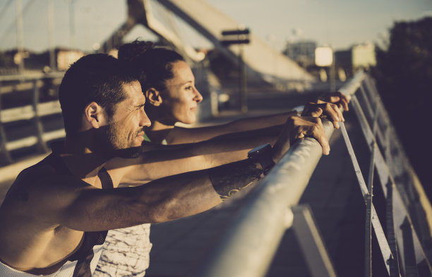 一对年轻的跑步者一边看日落一边做伸展运动图片下载
